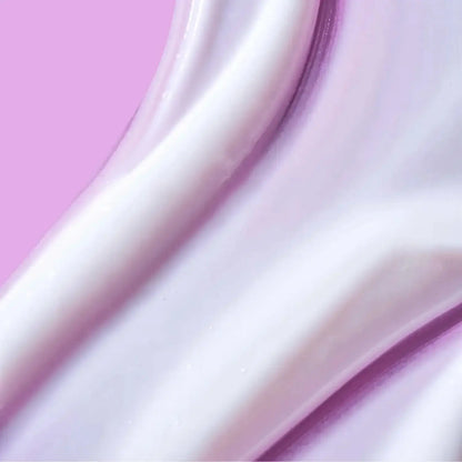 Close-up of creamy body lotion texture on a pink background, indicating smooth and hydrating qualities.