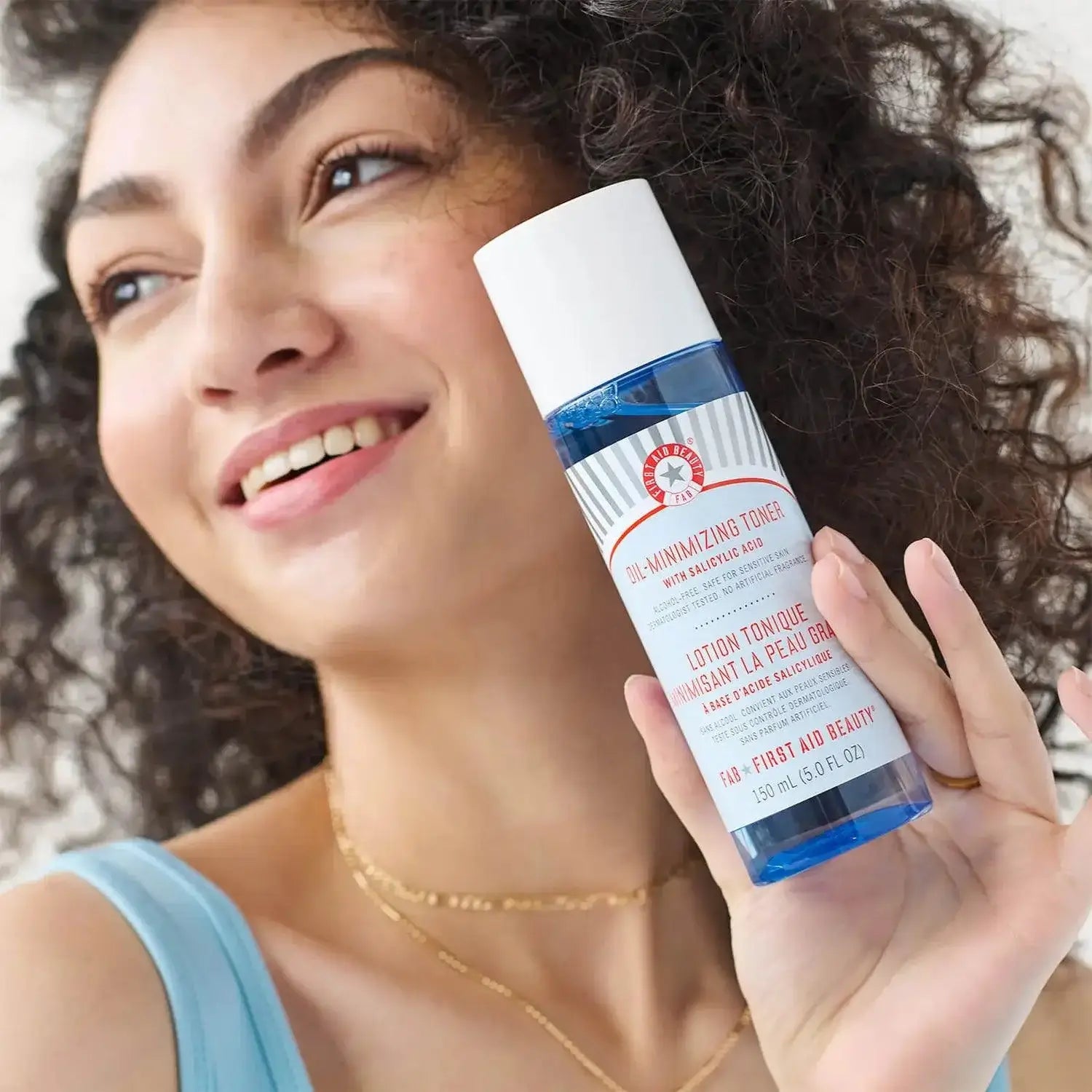 First Aid Beauty Oil-Minimizing Toner with Salicylic Acid in a woman's hand, promoting a clear complexion.