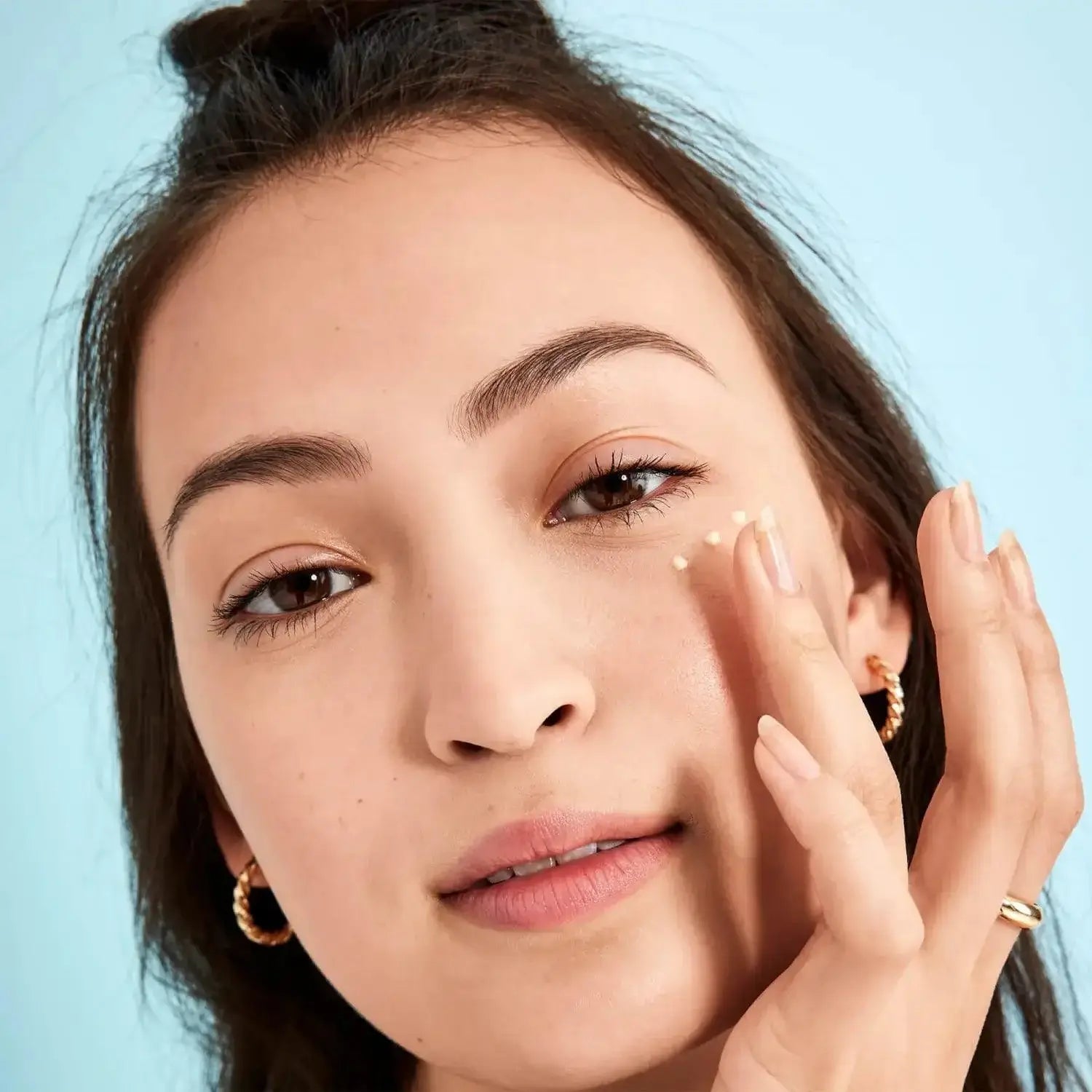 Woman applying First Aid Beauty Skin Lab Retinol Eye Cream to rejuvenate her eyes and reduce fine lines.