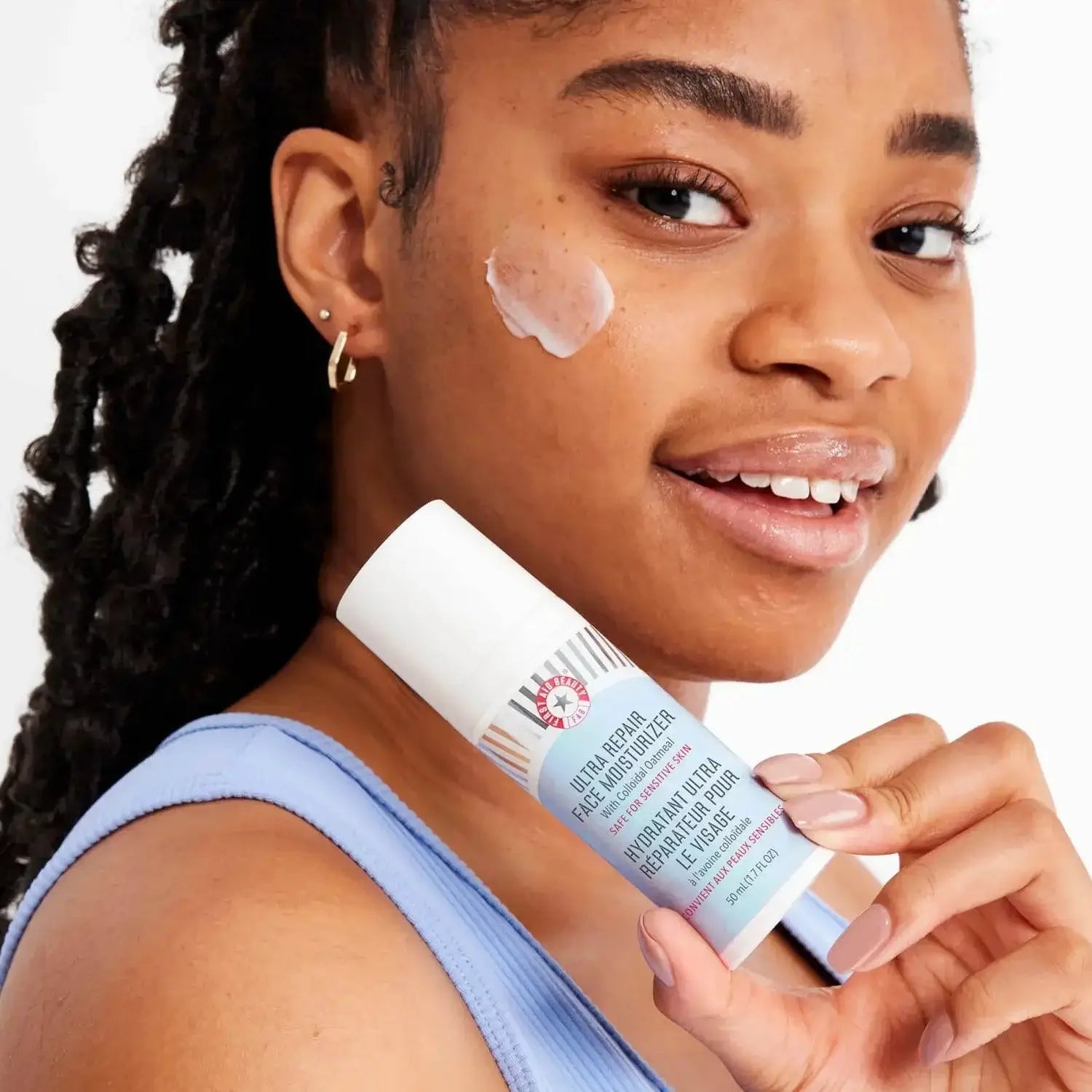 Woman applying First Aid Beauty Ultra Repair Face Moisturizer 50ml for instant hydration and soft skin.