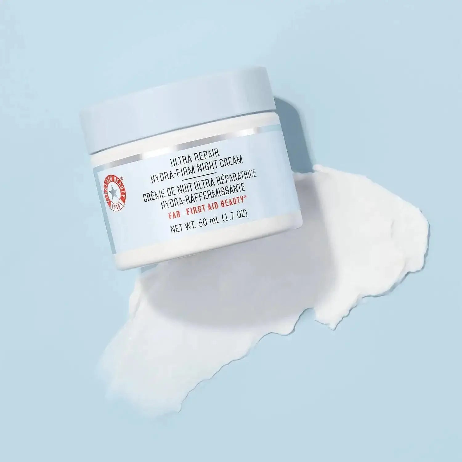 First Aid Beauty Ultra Repair Hydra-Firm Night Cream 50ml with a creamy texture on a blue background.