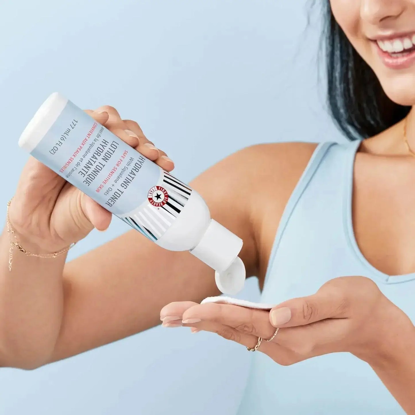 A person pouring First Aid Beauty Ultra Repair Wild Oat Soothing Toner into their palm, showcasing its hydrating formula.