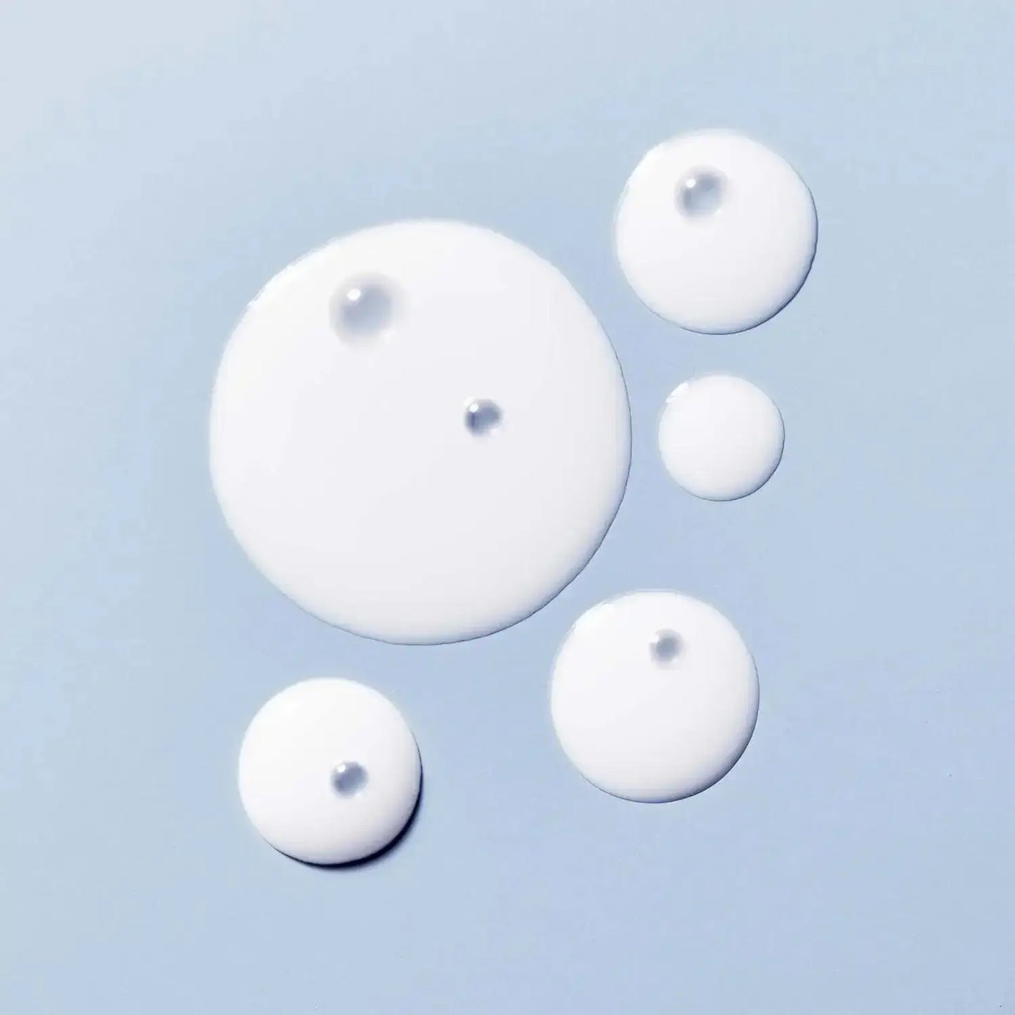 Droplets of creamy white toner, showcasing its lightweight and hydrating texture ideal for soothing the skin.