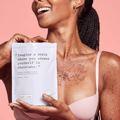 Woman holding a cacao coffee scrub packet with a pink background