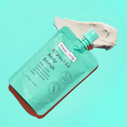 Green body scrub packaging with a swatch of scrub on a teal background