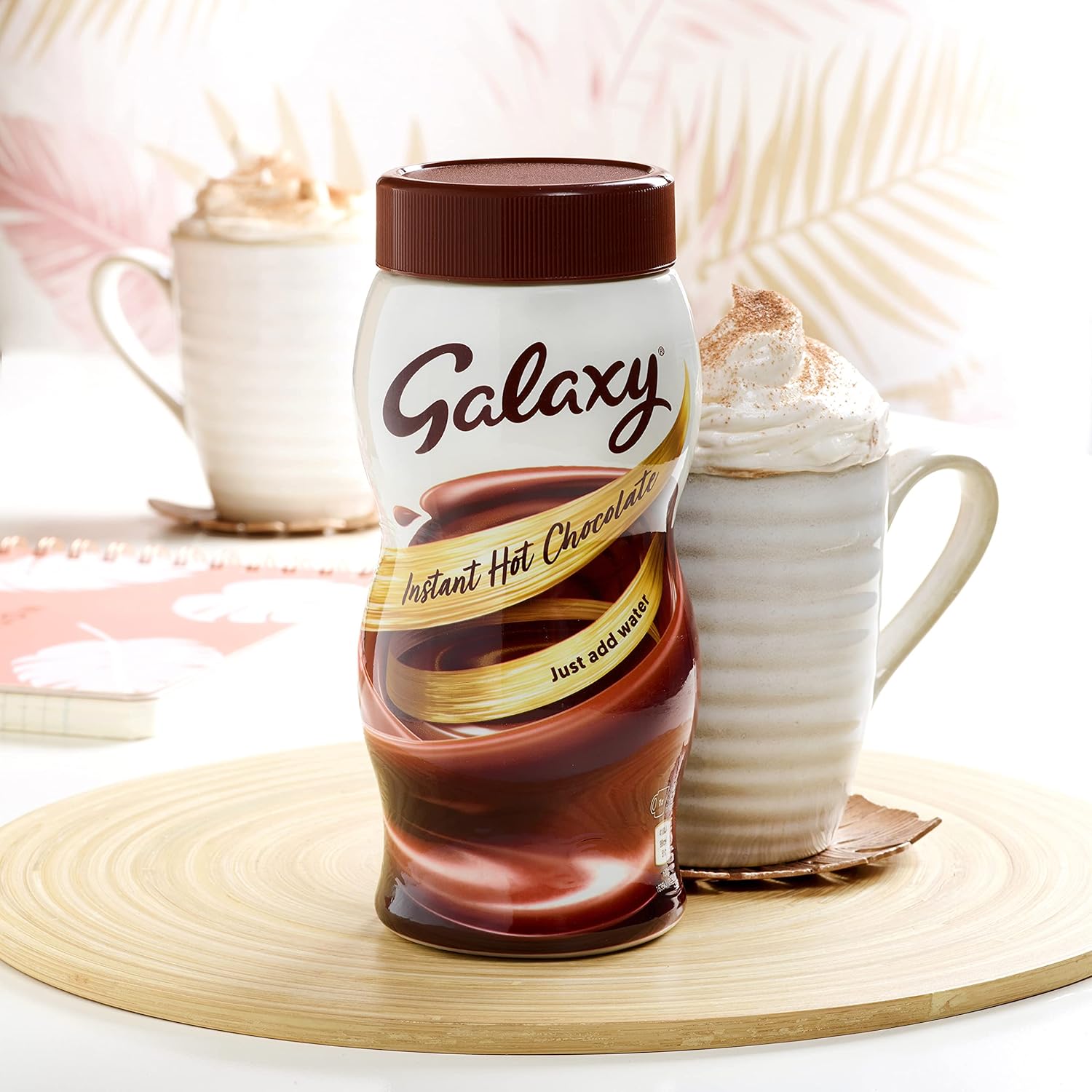 Galaxy instant hot chocolate jar with a mug of hot chocolate in the background