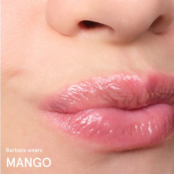 Close-up of lips with a Glossier glossy lip product, featuring the brand 'Mango'.