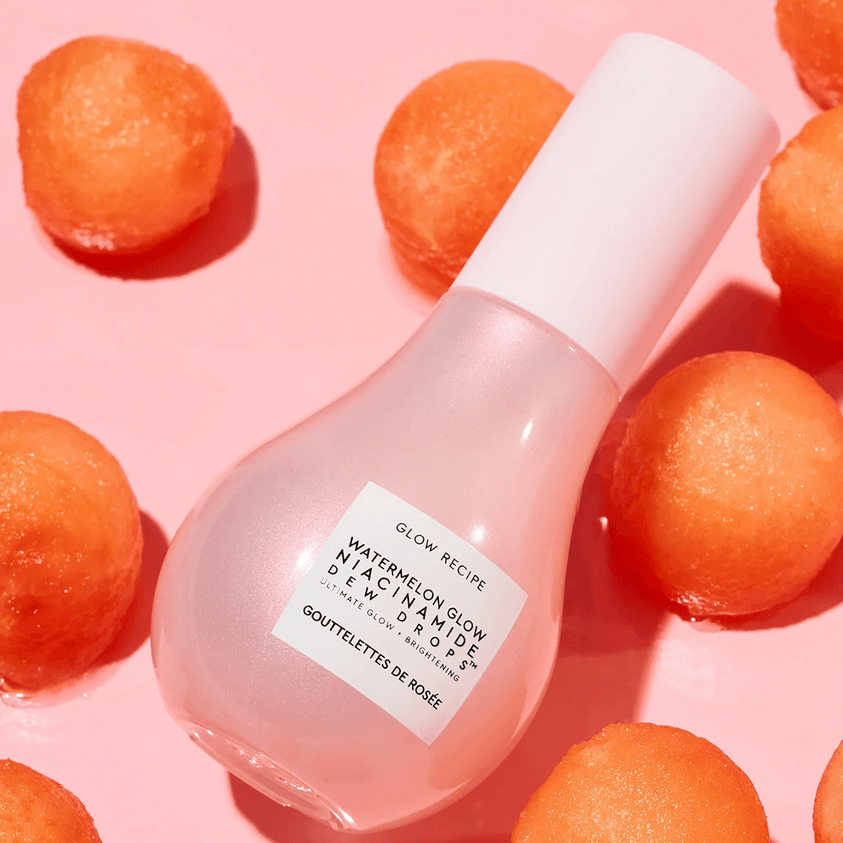 Glow Recipe Watermelon Glow Niacinamide Dew Drops bottle on pink backdrop with watermelon balls, perfect for radiant skin.