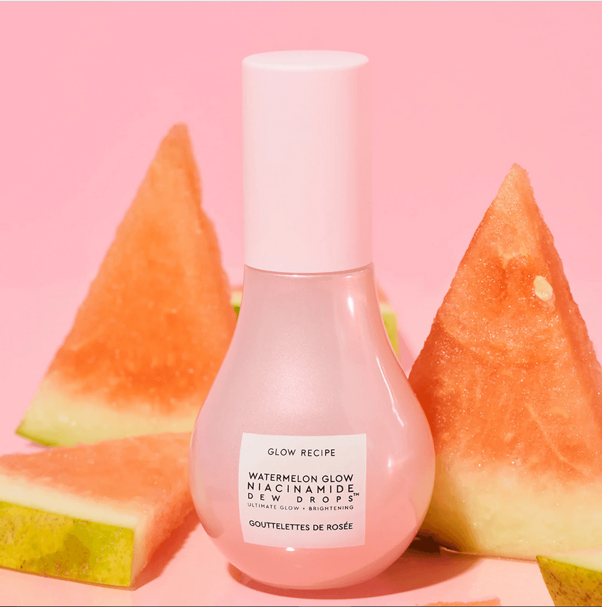 Glow Recipe Watermelon Glow Niacinamide Dew Drops bottle surrounded by fresh watermelon slices on a pink background.
