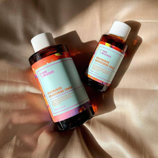 Two bottles of niacinamide brightening toner on a beige fabric background