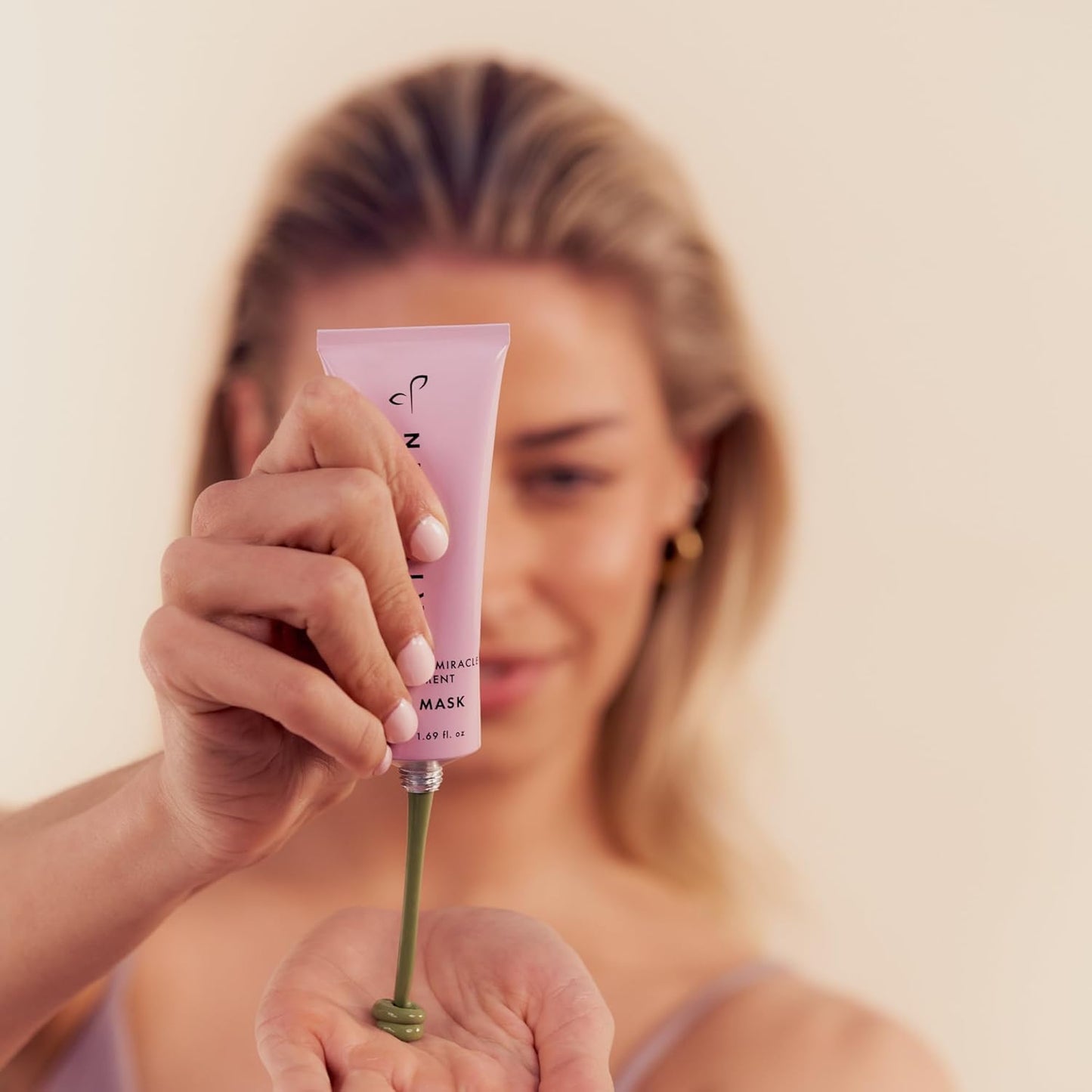 Woman holding a Hair Gain product with a blurred background