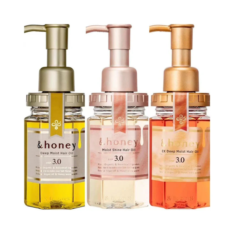 Three bottles of &honey hair oils with different colors and pump dispensers on a white background.
