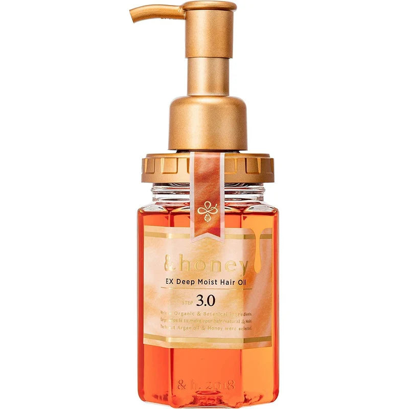 Hair oil bottle with gold pump and orange liquid on a white background