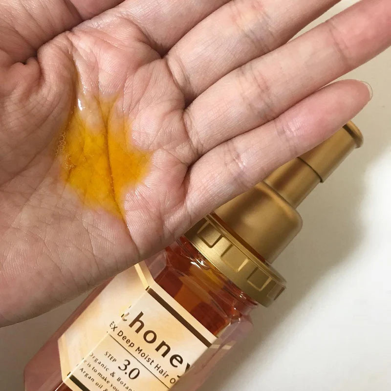 Hand holding a bottle of honey with a close-up of honey on the palm.
