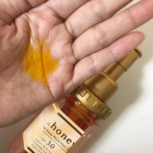 Hand holding a bottle of honey with a close-up of honey on the palm.