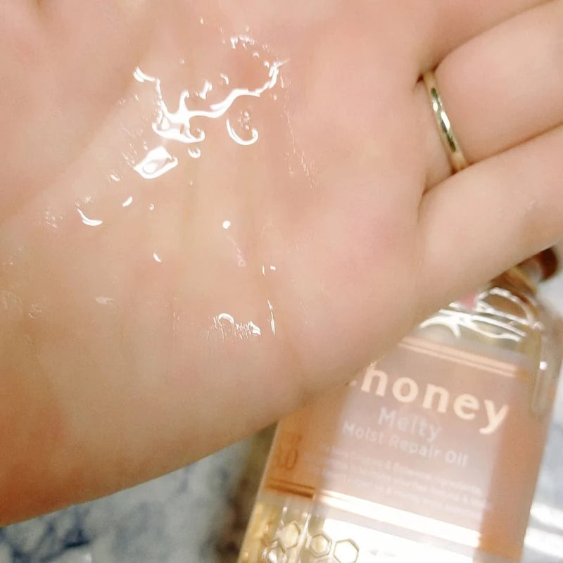 Hand applying a clear gel-like product to skin with a bottle labeled 'honey' in the background.