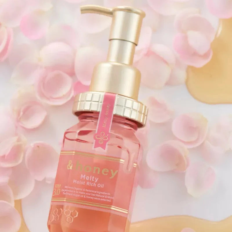 Bottle of 'Honey' oil with a gold pump on a soft pink floral background