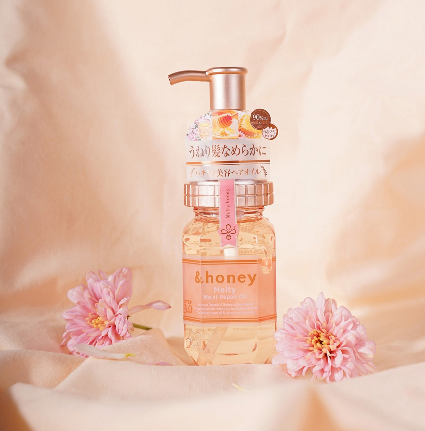 Bottle of &honey product with pink flowers on a soft beige background