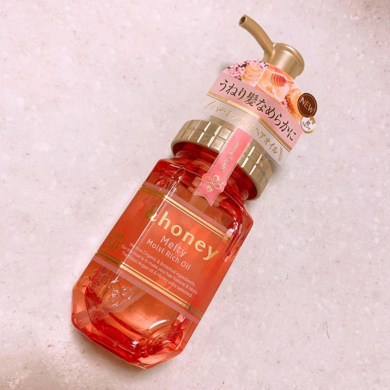Bottle of honey moisturizing hair oil on a textured beige background