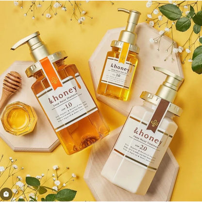 Three bottles of '& honey' skincare products on a yellow background with flowers and honeycomb.