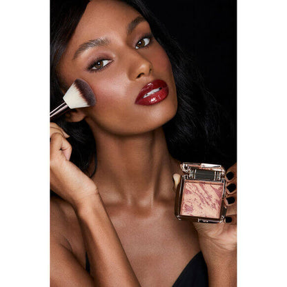 Model applying Hourglass Ambient Lighting Blush At Night with a brush, showcasing radiant skin and a luminous glow.