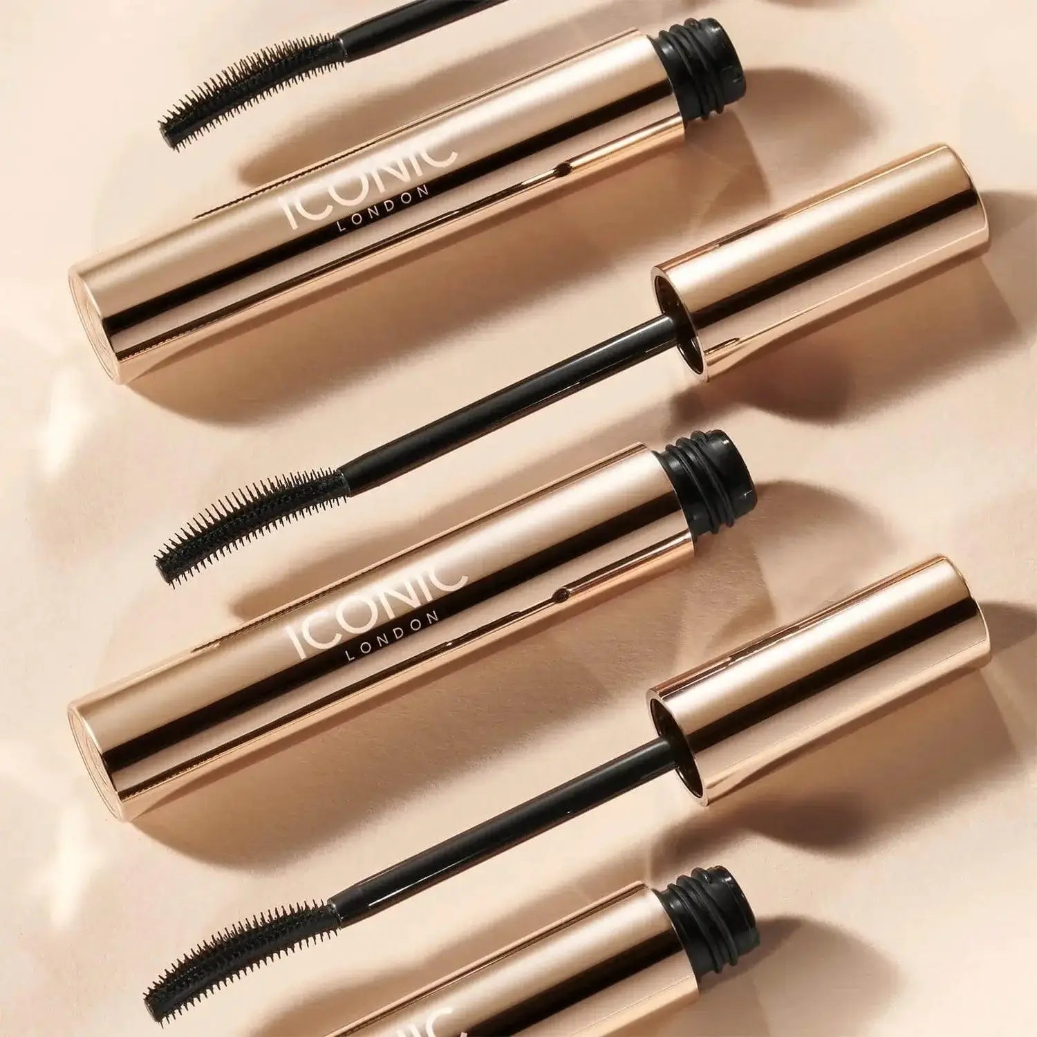 ICONIC London Enrich and Elevate Mascara in a sleek gold tube with wand, showcasing volumized lashes.