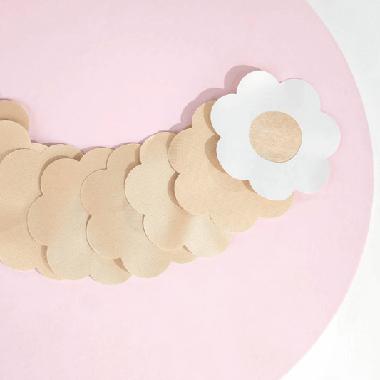 Brushworks Satin Petal Nipple Covers displayed on a pink background, featuring a smooth, discreet flower-shaped design.