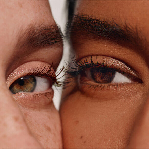 Close-up of two diverse eyes showcasing long, lush lashes, highlighting ILIA Limitless Lash Mascara's transformative effect.