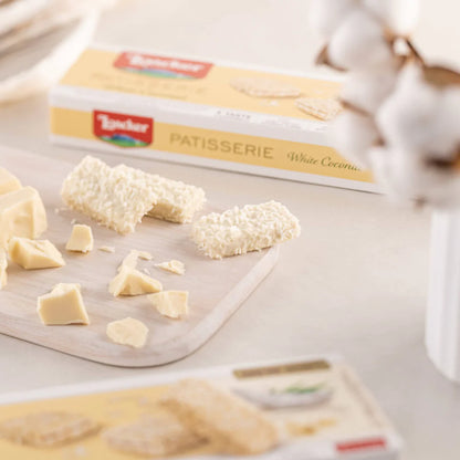 Loacker Patisserie White Coconut 100g with white chocolate and coconut pieces on a wooden board.