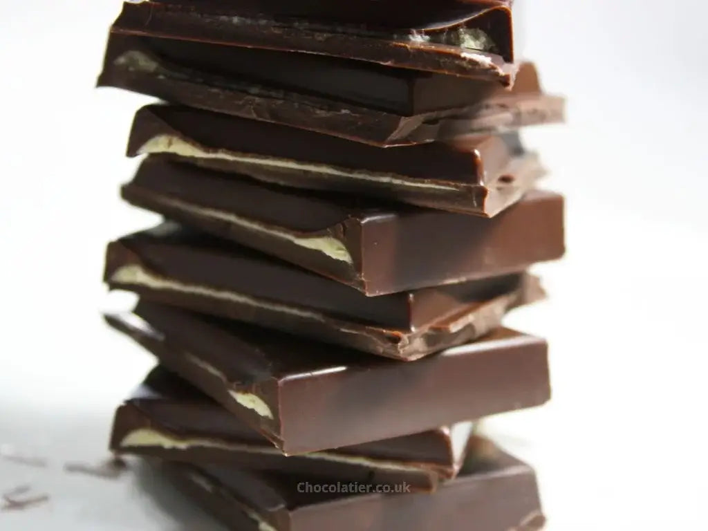 Lindt CREATION Dark Pistachio Bar stacked chocolate pieces showcasing rich dark chocolate layers.