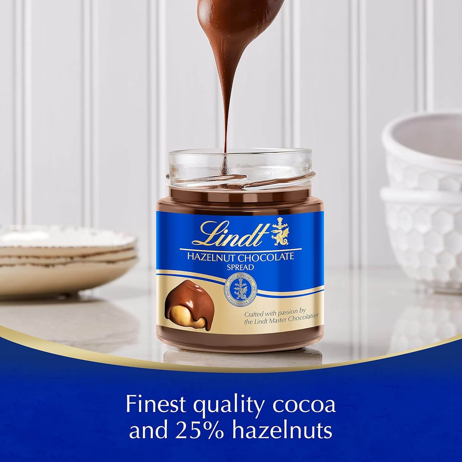 Lindt hazelnut chocolate spread being poured into a jar with a white background