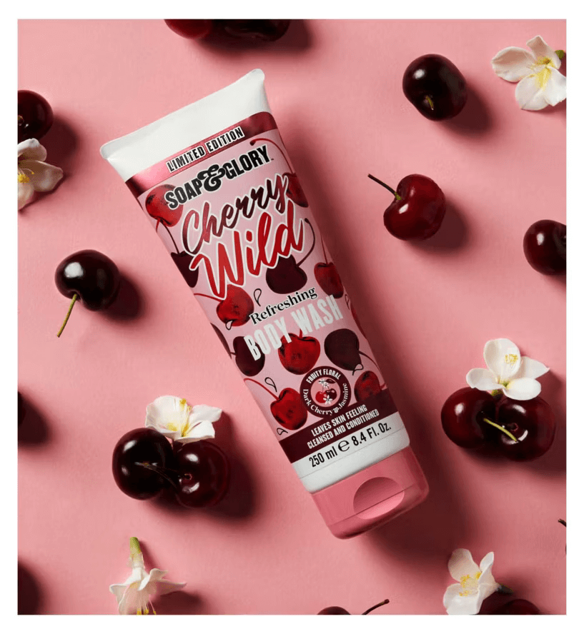 Soap & Glory Cherry Wild Refreshing Body Wash tube on a pink background with cherries and jasmine flowers.