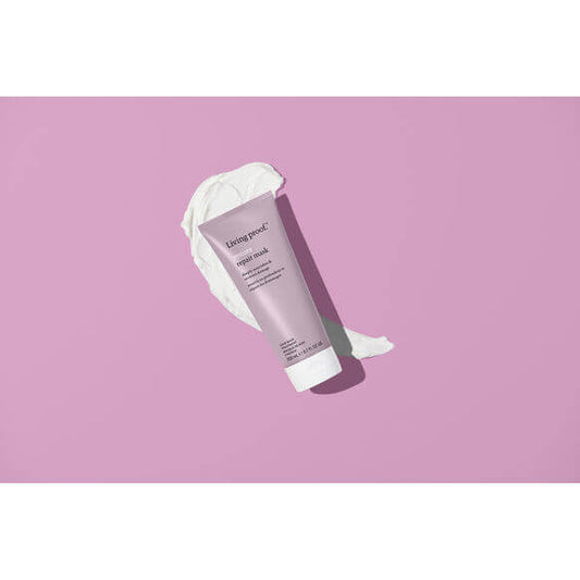 Purple tube of Living Proof skincare product with white applicator on a pink background