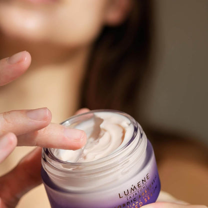 Person applying Lumene cream to their hand with a blurred background