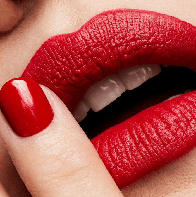 Close-up of a person wearing MAC bright red lipstick and nail polish.