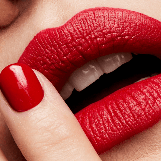 Close-up of a person wearing MAC bright red lipstick and nail polish.