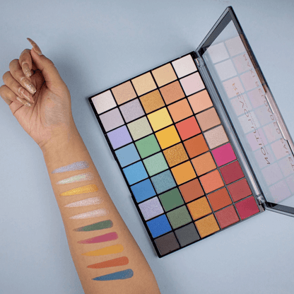 Revolution Maxi Reloaded Palette Monster Mattes with vibrant swatches on an arm, showcasing 45 ultra-pigmented shades.