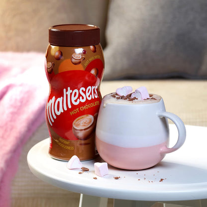 Maltesers hot chocolate jar with a pink and white mug on a table.
