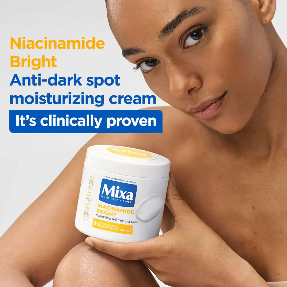 Woman holding a container of Mixa Niacinamide Bright cream against a gray background
