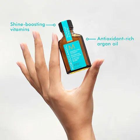 Moroccanoil Treatment 25ml bottle showcasing shine-boosting vitamins and antioxidant-rich argan oil in a hand.