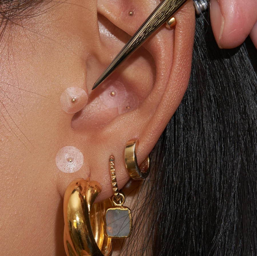 Close-up of a user's ear showcasing the Muihood 24K Gold Plated Ear Seed Kit and elegant jewelry.