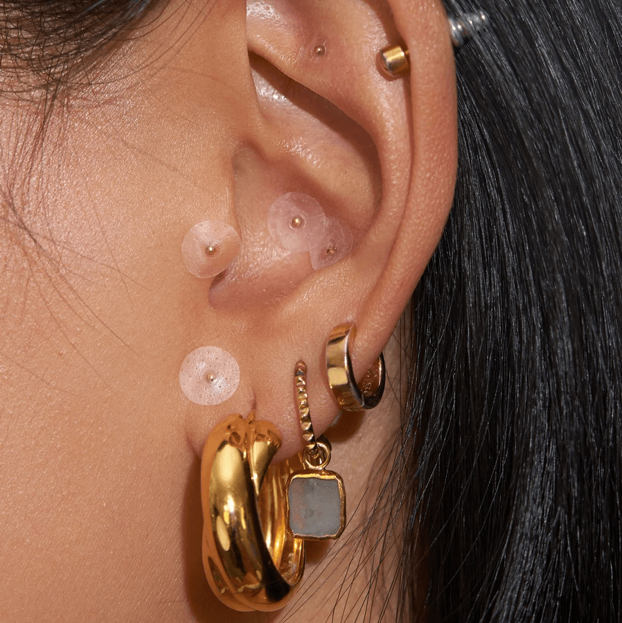 Close-up of a model's ear featuring Muihood 24K Gold Plated Ear Seed Kit for wellness and balance.