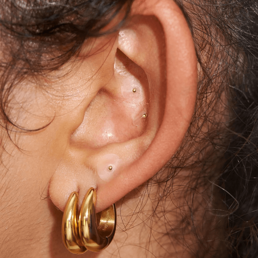 Close-up of a woman's ear with gold ear seeds, showcasing the Muihood 24K Gold Plated Ear Seed Kit.