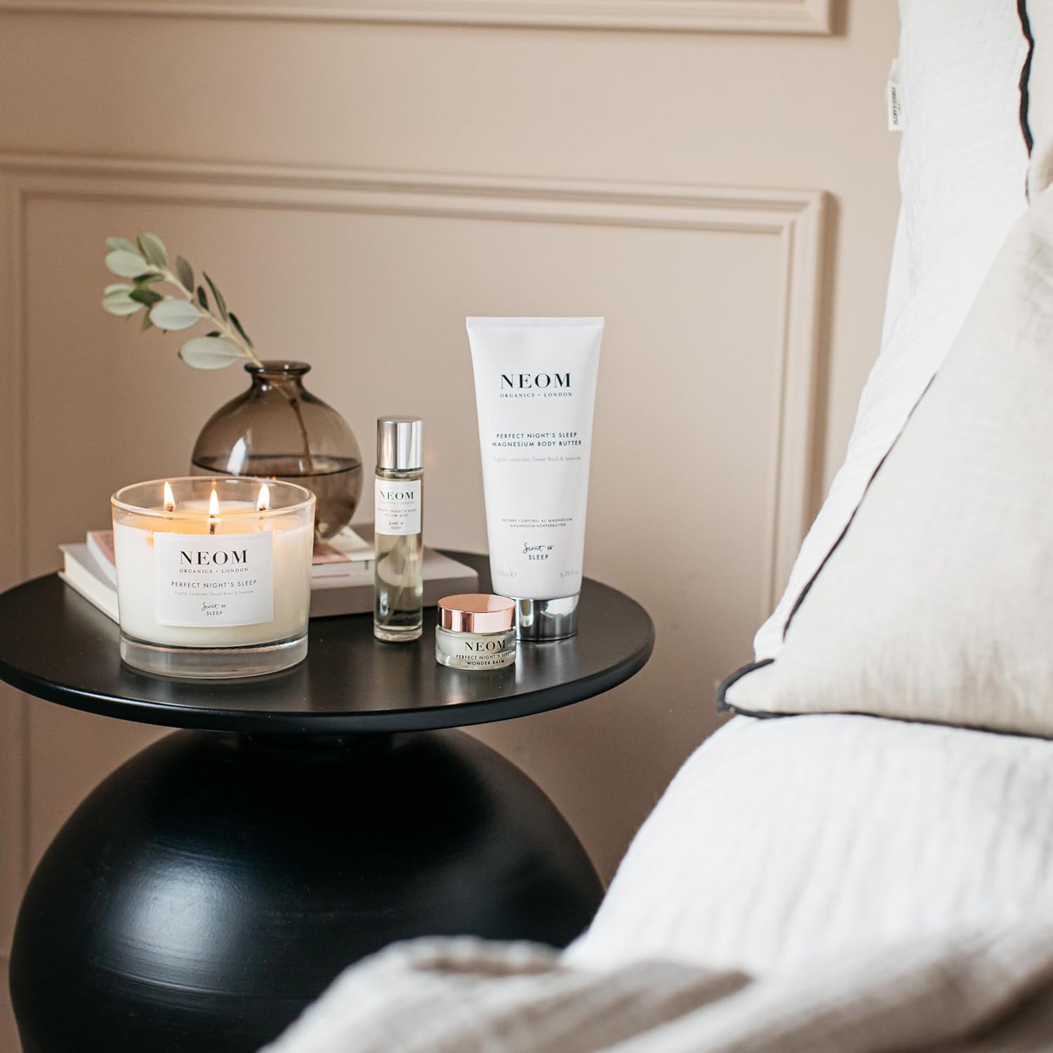 NEOM products including a candle, bottle, and tube on a table with a neutral background