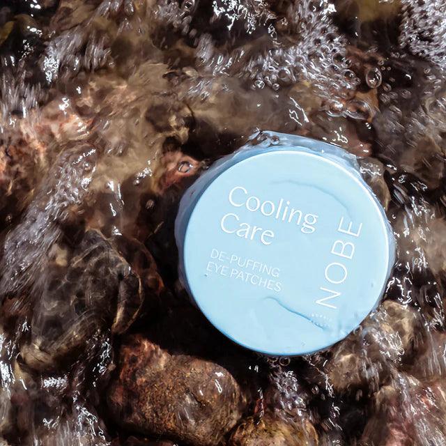 NOBE Cooling Care De-Puffing Eye Patches on rocks with flowing water, highlighting their refreshing skincare qualities.