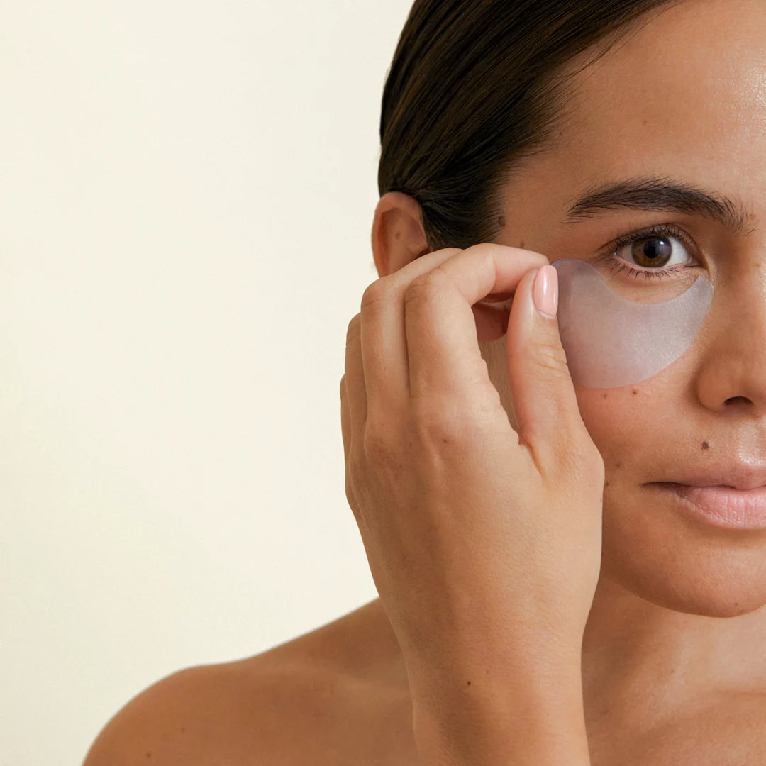 Woman applying NOBE Arctic Skincare cooling eye patches for de-puffing and hydration.