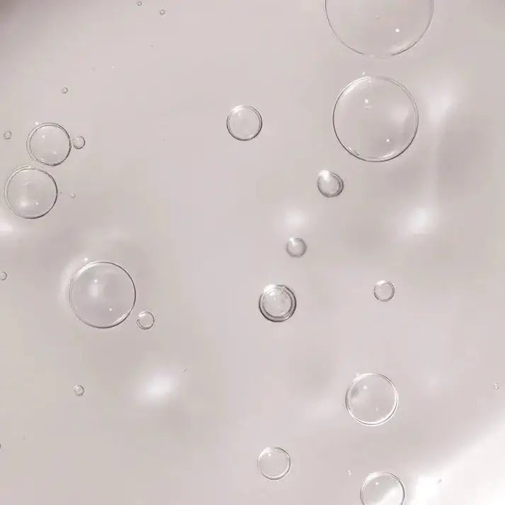 Close-up of bubbles in a clear liquid, showcasing the lightweight texture of ARKIVE The Good Habit Hybrid Oil.