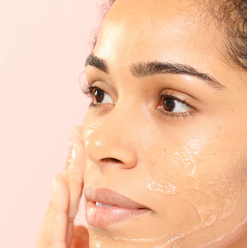 Close-up of a woman's face with a NUXE skincare product applied on a pink background