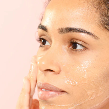 Close-up of a woman's face with a NUXE skincare product applied on a pink background