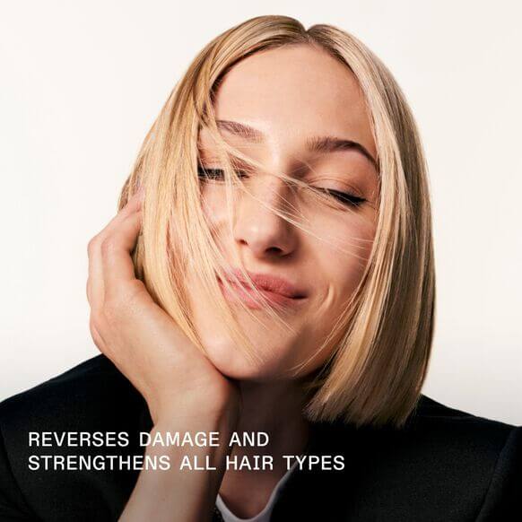 Woman with blonde hair touching face against a white background, text 'Olaplex Reverses damage and strengthens all hair types' below.